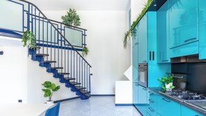 Une cuisine moderne avec des meubles bleus, une cuisinière à gaz et un escalier avec des rampes bleues.