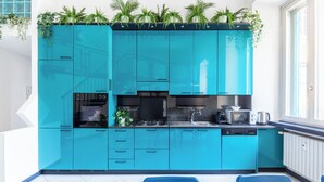 Une cuisine moderne avec des meubles de couleur turquoise, une cuisinière encastrée, un four à micro-ondes et un lave-vaisselle.
