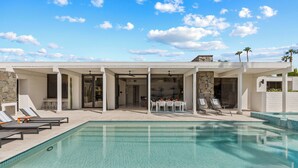 A modern outdoor pool area with lounge chairs and a covered seating area.