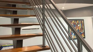 Un interior moderno con una escalera espiral, un espejo decorativo y un cuadro abstracto de colores vivos.