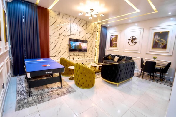 Una sala de estar moderna con una mesa de ping pong, sillones amarillos, un sofá negro y un comedor con mesa y sillas.