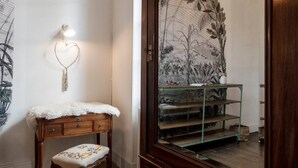 Una habitación con un banco de madera, una lámpara con forma de corazón y un gran mural botánico en la pared.