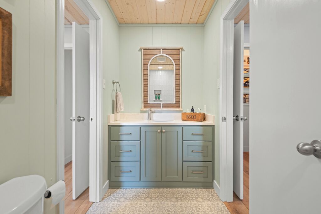 A bathroom with a vanity, sink, and mirror. There are cabinets and drawers for storage.