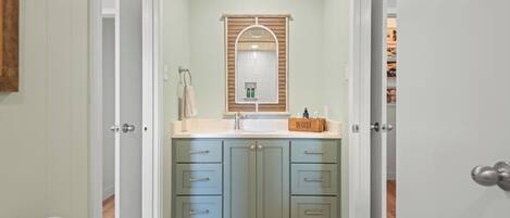 A bathroom with a vanity, sink, and mirror. There are cabinets and drawers for storage.