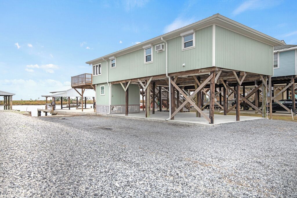 A two-story building with a wooden deck structure, a covered outdoor seating area, and a gravel ground.