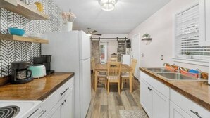 A modern kitchen with white cabinets, a wooden dining table, and a built-in oven. - Charming Midtown Home w/ Private Patio; Mardi Gras (AL)