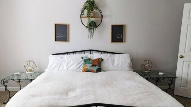 A bedroom with a bed, two bedside tables, and wall art. - Cozy Midtown Mobile Home; Fireplace & Pet-Friendly (AL)