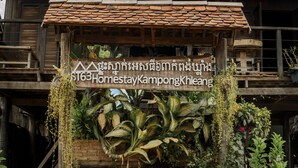 Een houten constructie met een bord waarop 'ST63 Homestay Kampong Kheang' staat.