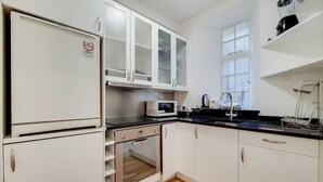 A kitchen with white cabinets, a microwave, a stove, and a sink. - Quebec Residence (London)