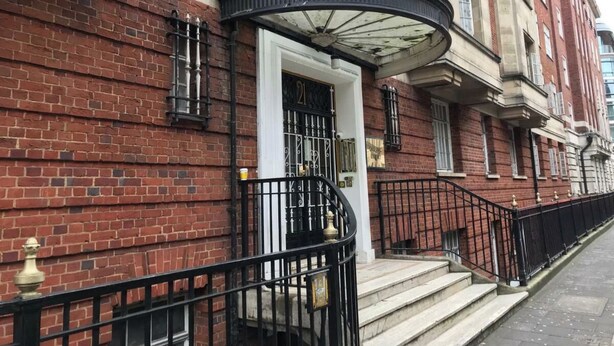 A red brick building with a white door and black iron railing. - Quebec Residence (London)