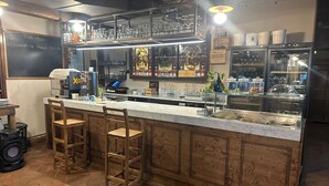 A bar area with a marble countertop, stools, and a chalkboard menu.