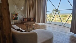 Un salón amplio con un gran ventanal, un sofá, una mesa de centro y un cuadro en la pared.