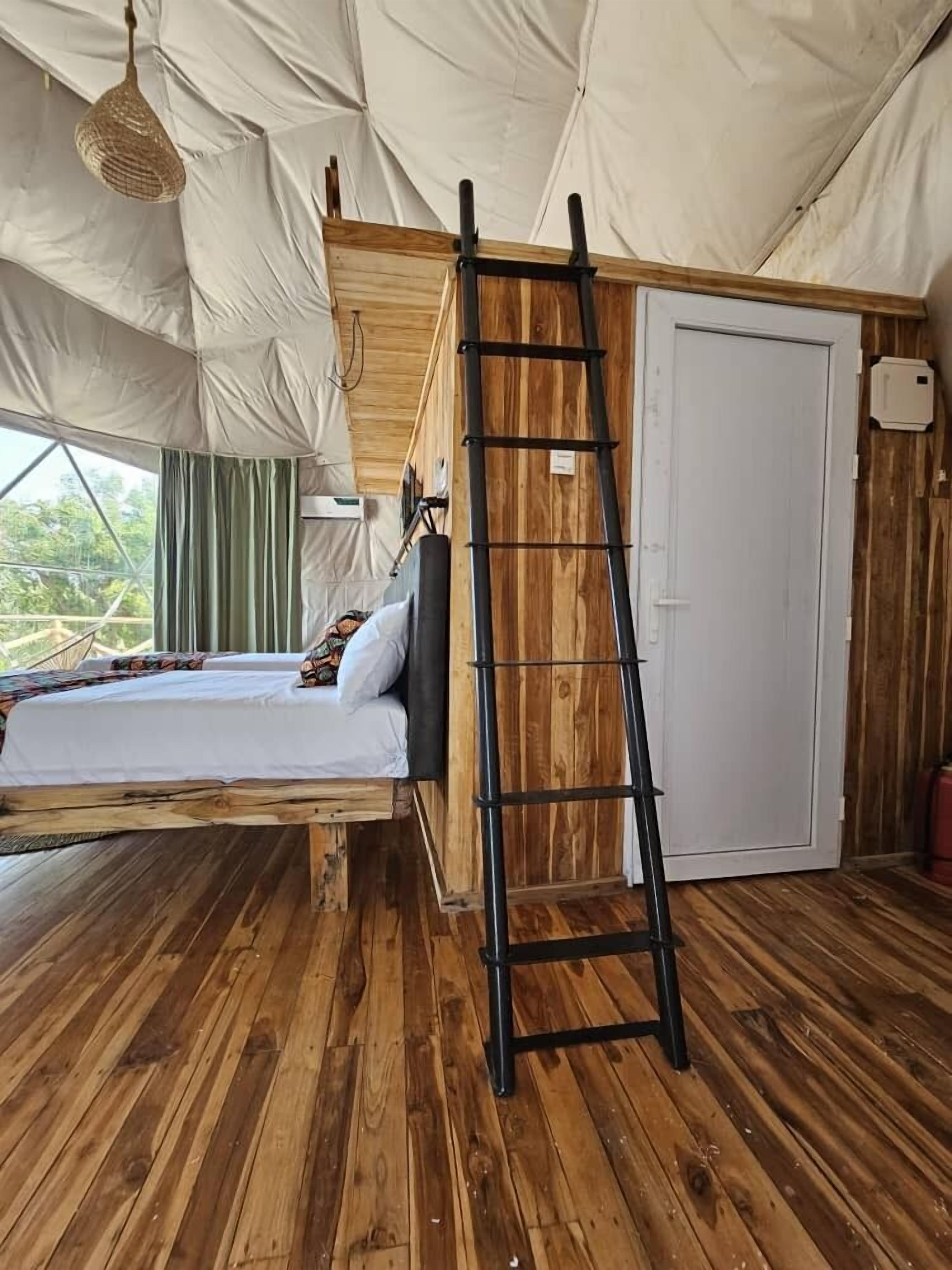 Una habitación con carpa, una cama, una escalera y un armario.