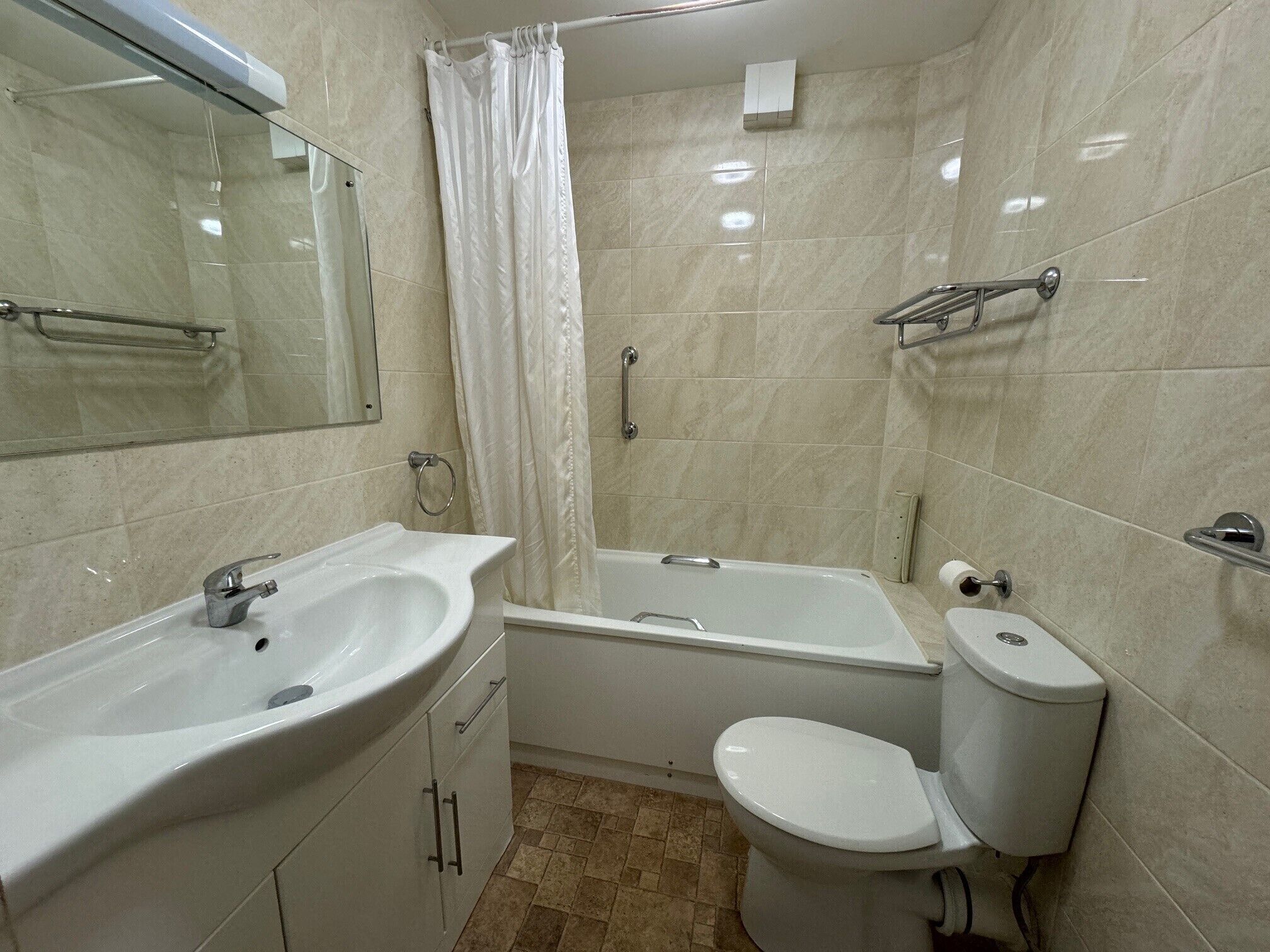A bathroom with a sink, toilet, bathtub, and a shower curtain.