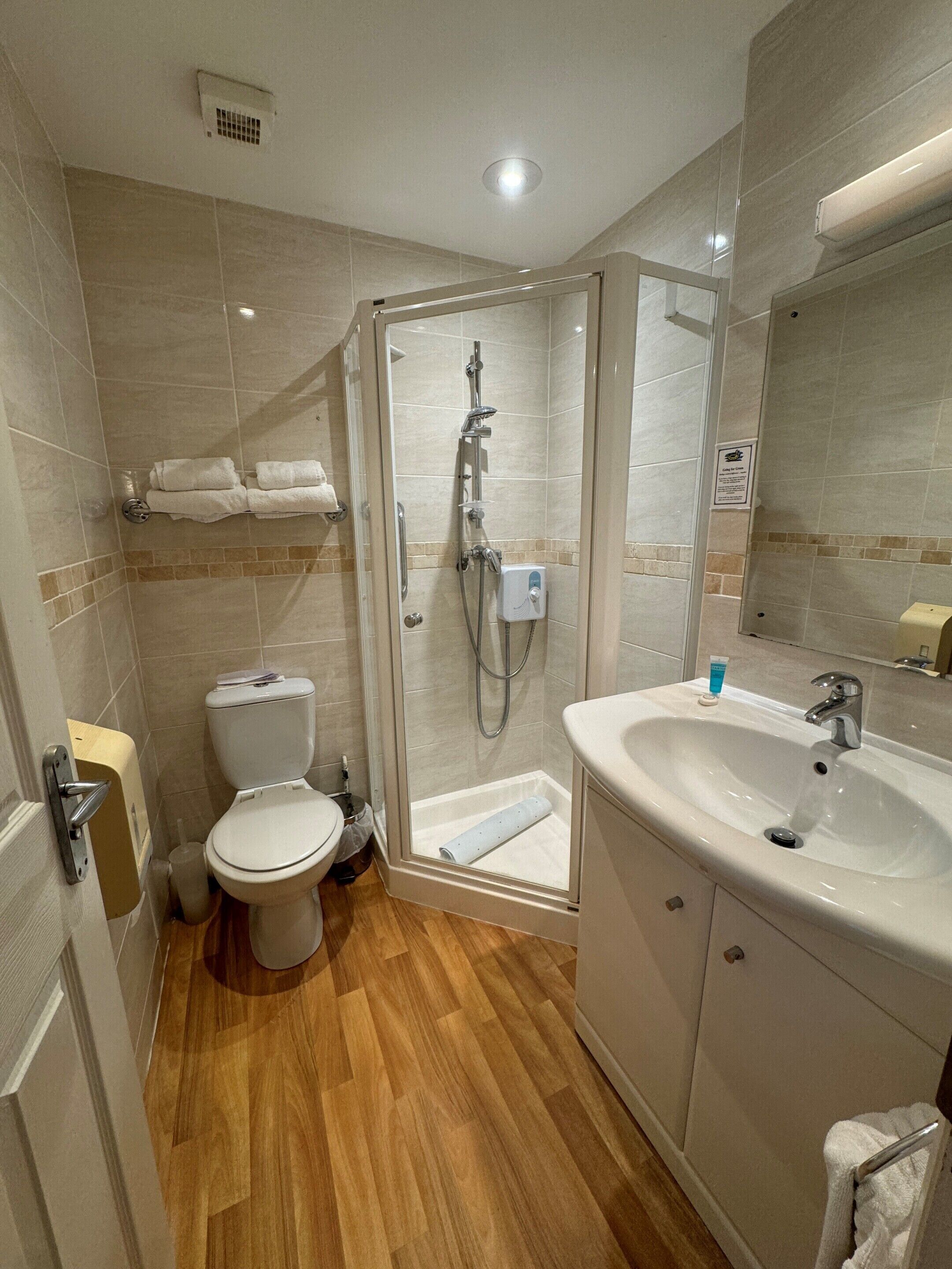 A modern bathroom with a glass-enclosed shower, a white sink, and a toilet.