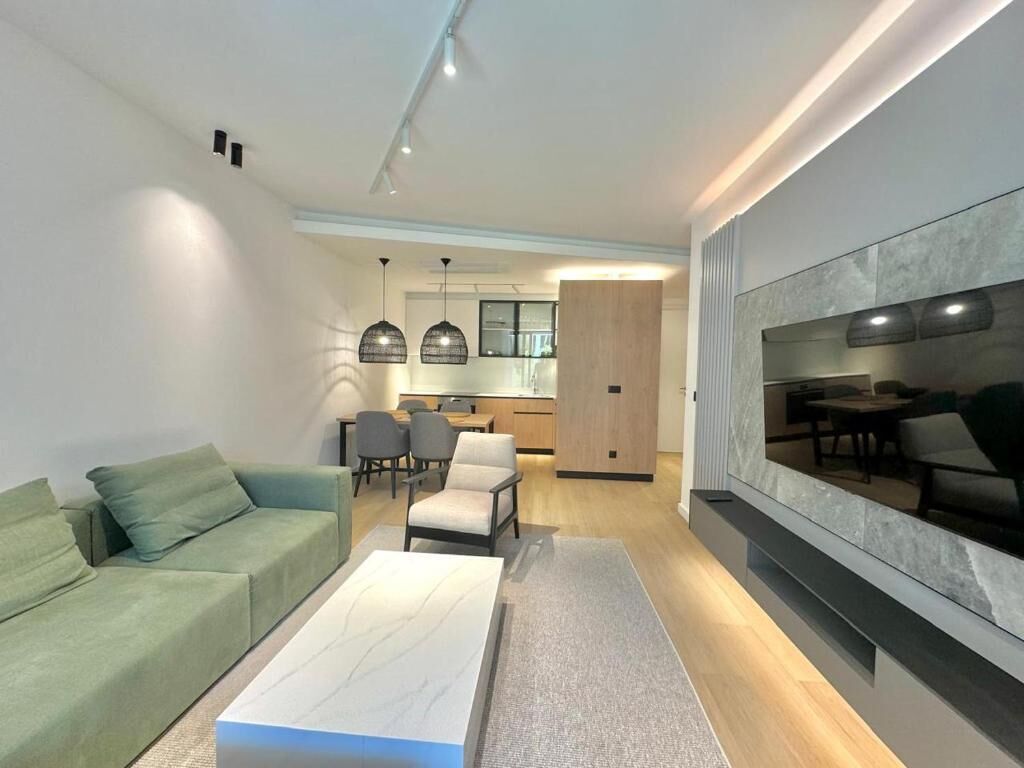 A modern living room with a sofa, a coffee table, and a TV mounted on the wall.
