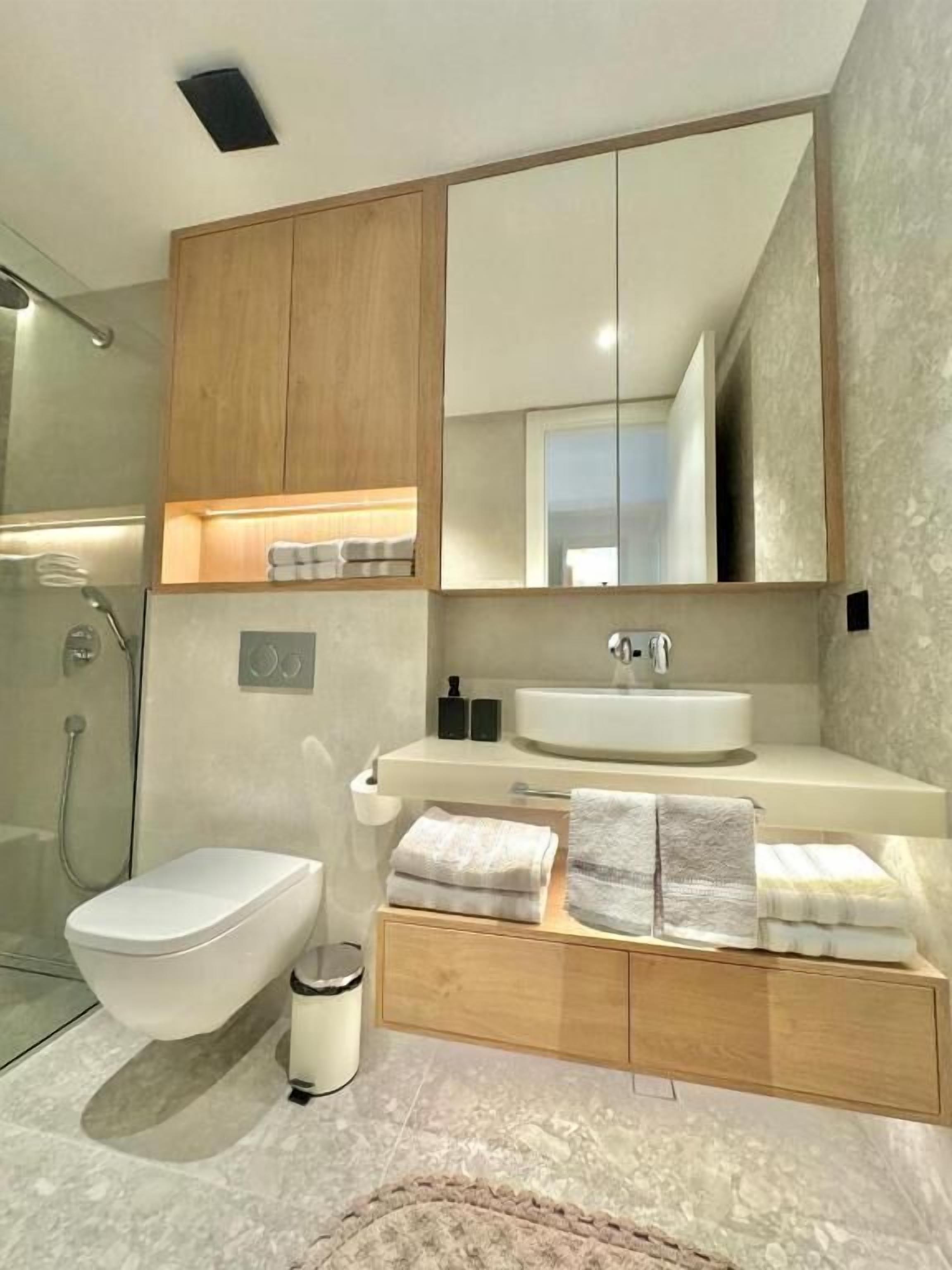 Un baño moderno con inodoro, lavamanos y ducha.