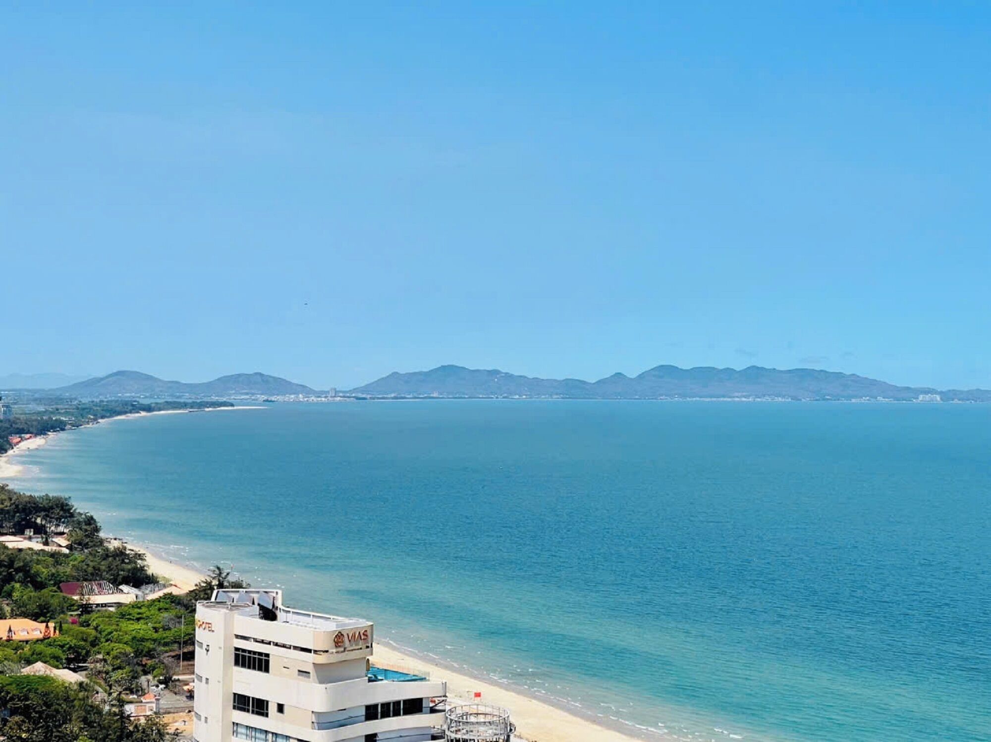 Un hôtel en bord de mer offrant une vue sur la plage, une piscine et un ciel dégagé.
