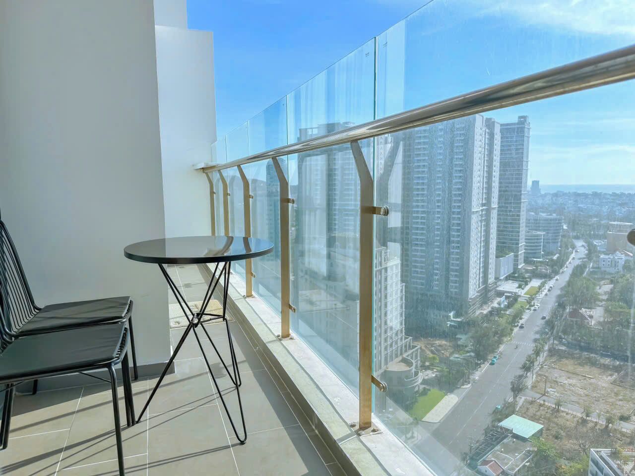 Un balcon doté d’une balustrade en verre, d’une chaise noire et d’une petite table ronde.