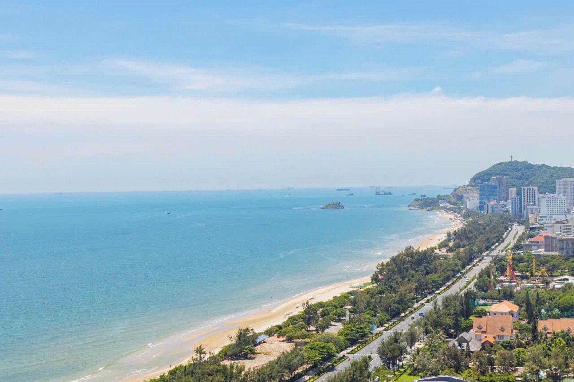 Eine Küstenstadt mit Strand, Gebäuden und hügeliger Landschaft im Hintergrund.