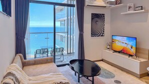 Un soggiorno moderno con una grande TV, un divano e un balcone vista mare.