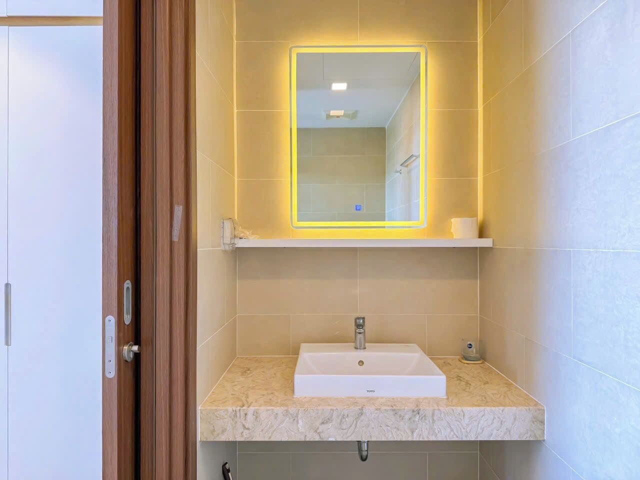 A bathroom with a white sink, a mirror, and a shelf above the sink.