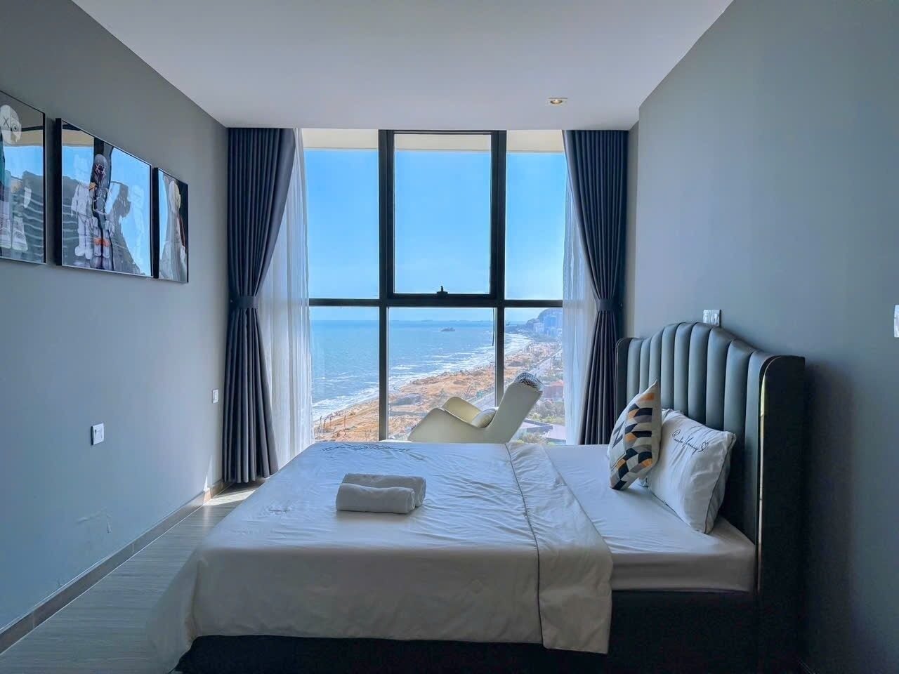 A bedroom with a large window, a bed, and a chair.