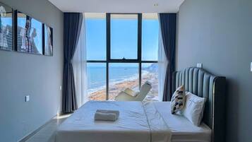 A bedroom with a large window, a bed, and a chair.