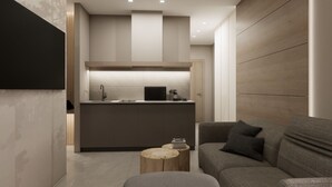A modern living room with a grey sofa, a round coffee table, and a kitchen area with a central island and built-in appliances. - Bellettinihome (Cervia)
