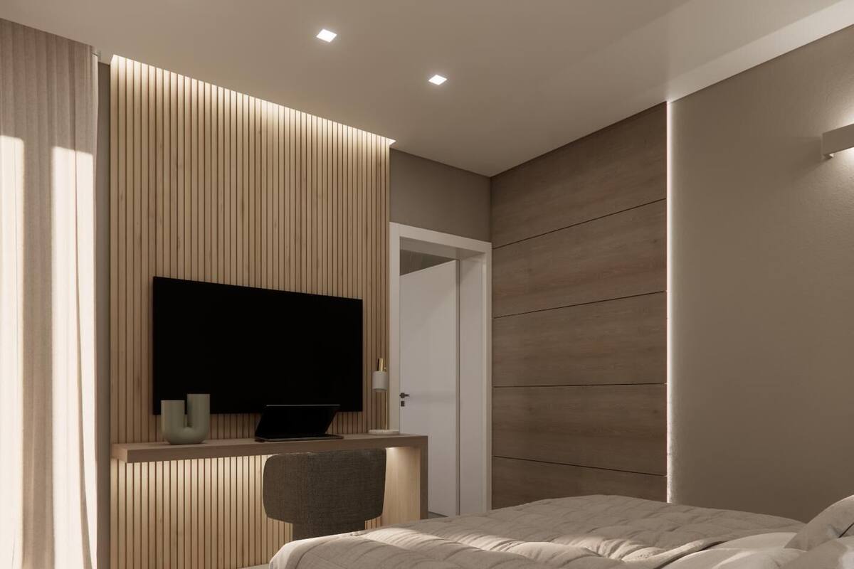Ein modernes Schlafzimmer mit einem Bett, einem Schreibtisch mit Laptop, einem an der Wand montierten Fernseher und einer Tür zu einem anderen Raum.