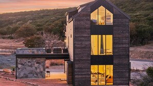 A modern house with a large glass window and a stone wall.