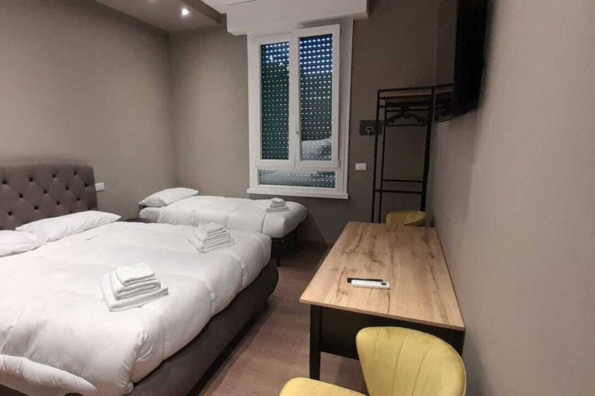 A bedroom with two beds, a wooden table, and a chair.
