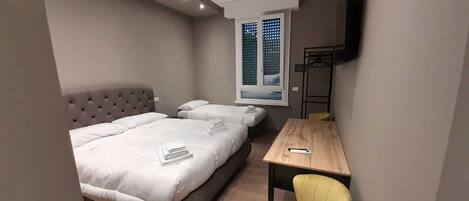 Un dormitorio con dos camas, una mesa de madera y una silla.