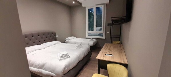 Un dormitorio con dos camas, una mesa de madera y una silla.