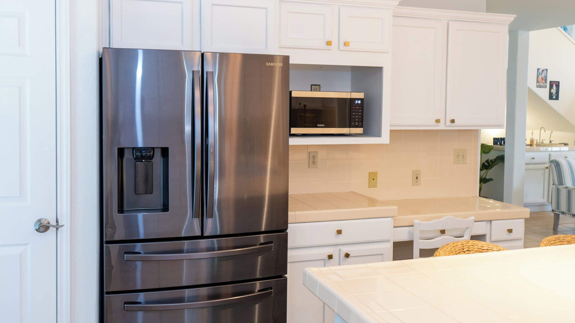 A modern kitchen with stainless steel appliances, white cabinetry, and a built-in microwave.