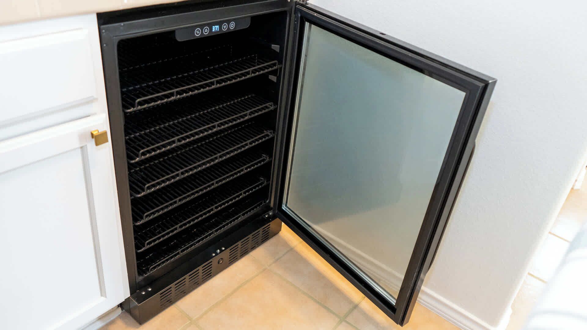 A compact refrigerator with a freezer compartment, built into a kitchen cabinet.