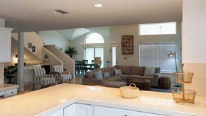 A spacious living area with a large sectional sofa, a kitchen with a white countertop, and a dining area with a table and chairs. - Upscale & Spacious Home - Renovated - Pool (South Padre Island)