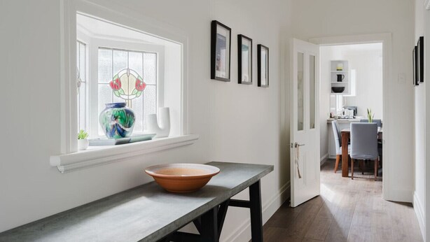A hallway with a window, a bowl on a table, and a kitchen in the background. - Navi Home, stay like locals (Yarraville)