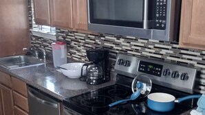 Una cocina con armarios de madera, un microondas de acero inoxidable, una estufa a gas y un horno empotrado.