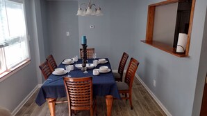 Un comedor con mantel azul, sillas de madera, candelabro y espejo en la pared.