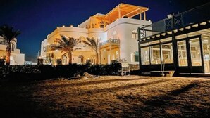 Un hotel moderno con fachada curva, varios balcones y una zona exterior cubierta.
