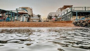 Un hotel frente a la playa con varias construcciones, incluyendo una estructura con zona cubierta y otra con balcón.