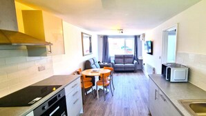 A compact kitchen with a dining area, a built-in oven, and a microwave. - Beachfront apartment with direct beach access! (Perranporth)