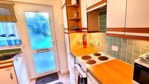 A kitchen with a stove, a fire extinguisher, and a sink.