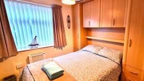A bedroom with a bed, wooden wardrobe, and a window with curtains.
