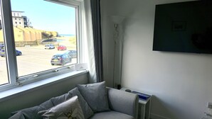 Une chambre avec une fenêtre donnant sur un parking et la plage.