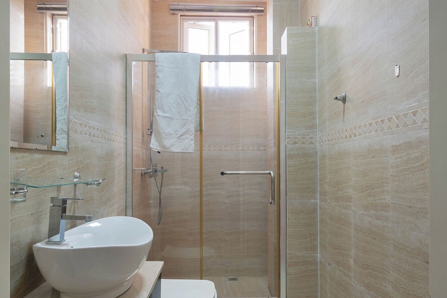Une salle de bain avec une douche à parois de verre, un lavabo blanc et un miroir au-dessus.