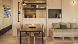A compact living space with a dining table, chairs, a sofa, and built-in kitchen shelves. - wecamp Cádiz (Puerto Real)