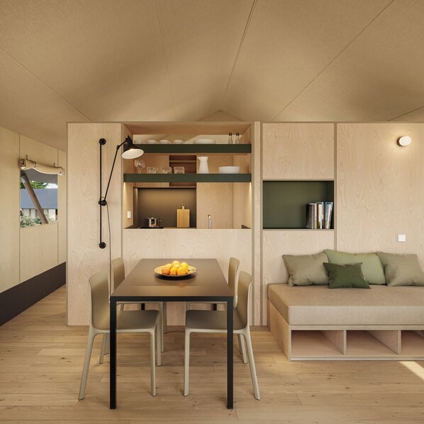 A compact living space with a dining table, chairs, a sofa, and built-in kitchen shelves. - wecamp Cádiz (Puerto Real)