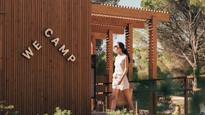 A wooden structure with the text "WE CAMP" on a vertical panel. - wecamp Cádiz (Puerto Real)
